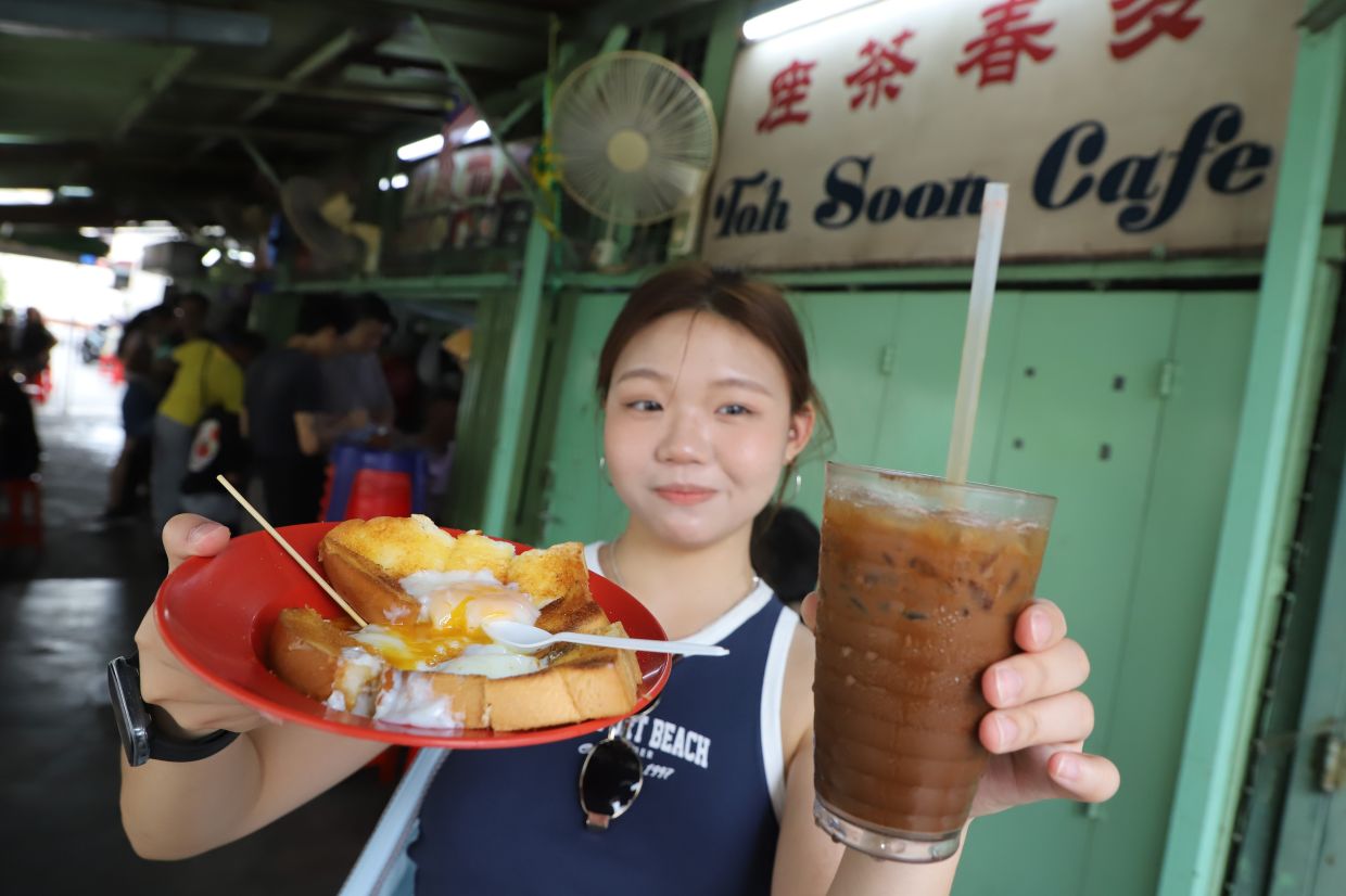 Carol Ler, 21, from Johor having coffee and breakfast in Toh Soon Cafe. — LIM BENG TATT/The Star
