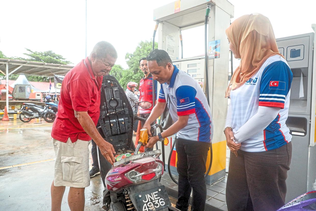 Aznan (second from right) helping a motorcyclist fuel up during the ‘Jelajah Orang Johor’ tour in Tanjung Surat constituency, Kota Tinggi.