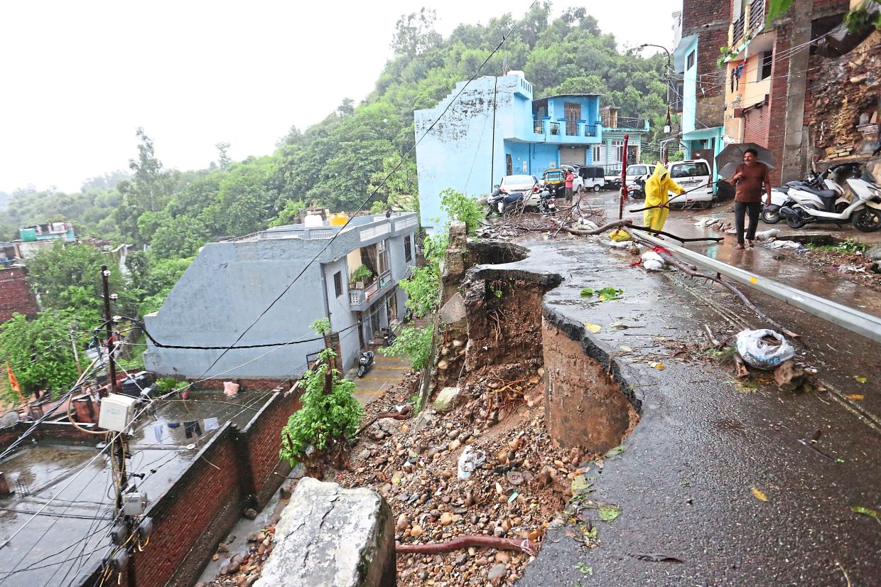 While people look at the collapsed road after the downpours in Jammu.