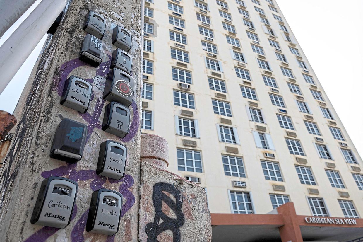 Airbnb lock boxes attached to a light pole in front of a residential building in San Juan. — AFP