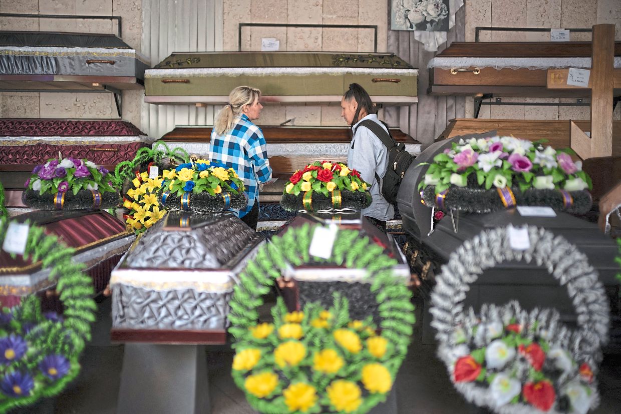 An employee at a funeral home shows coffins to a grieving woman.