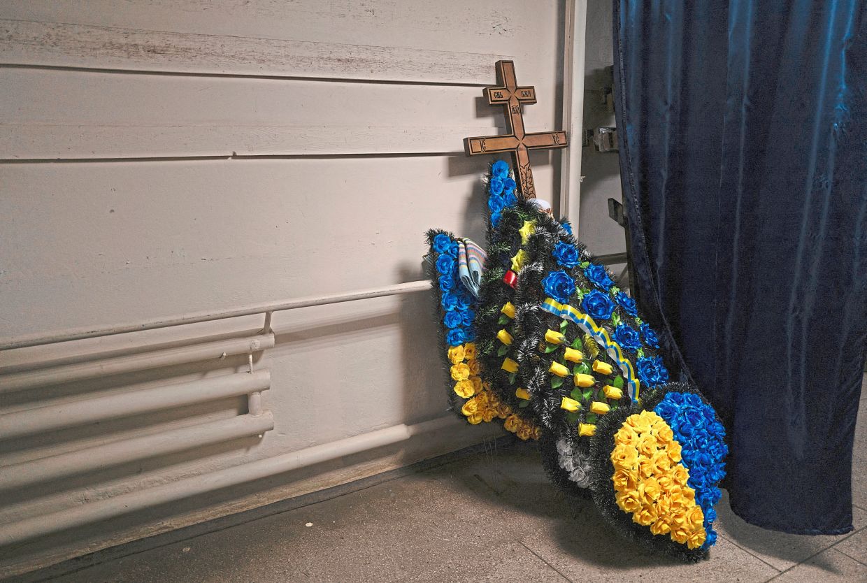 A cross and wreaths of flowers placed against a wall at the funeral home.