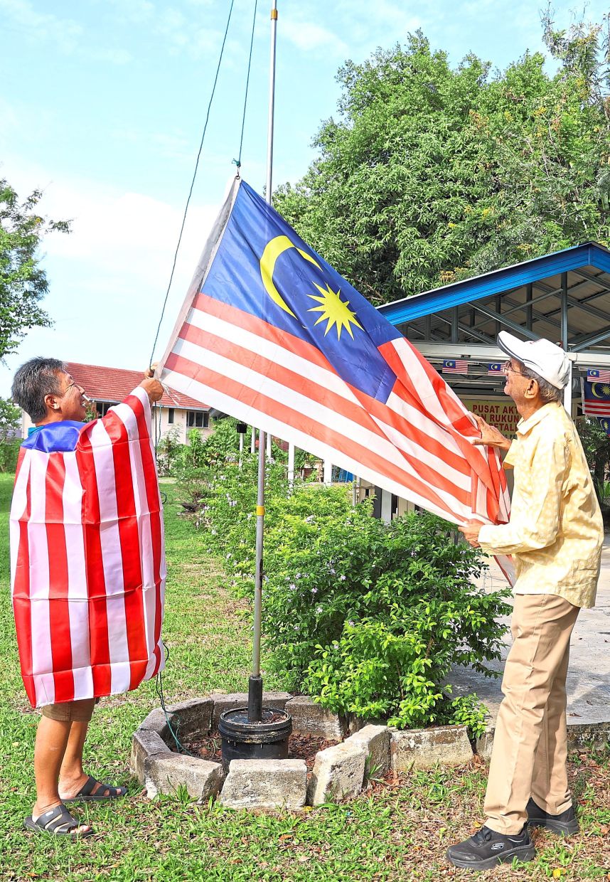 Rajesh (right) putting up several Jalur Gemilang in Section 6 Petaling Jaya with help from a fellow resident. — Photos: MUHAMAD SHAHRIL ROSLI and LOW LAY PHON/The Star and courtesy pix