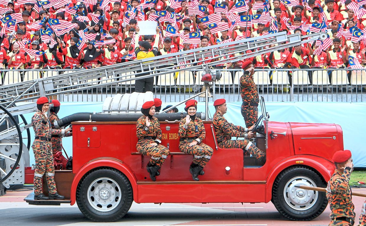 Fire and Rescue Department personnel on a fire engine during the march-past. — Photos: AZHAR MAHFOF and FAIHAN GHANI/The Star