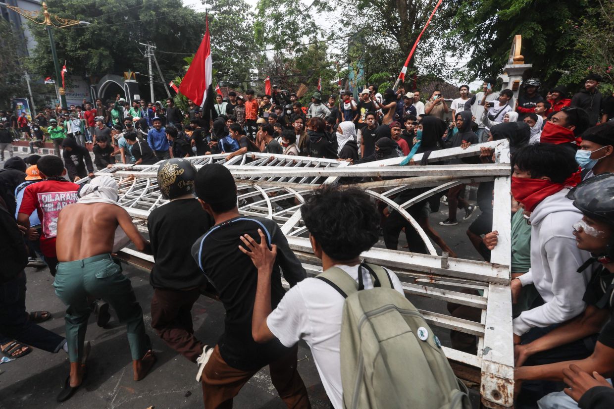 Protesters tear down the fence of the West Nusa Tenggara Provincial Council office during a demonstration in Mataram on Lombok Island, West Nusa Tenggara, on August 30, 2025. Indonesia was rocked by protests in major cities, including the capital Jakarta, after footage spread of a motorcycle taxi driver being run over by a police tactical vehicle in earlier rallies against low wages and financial perks for lawmakers. -- Photo by AFP