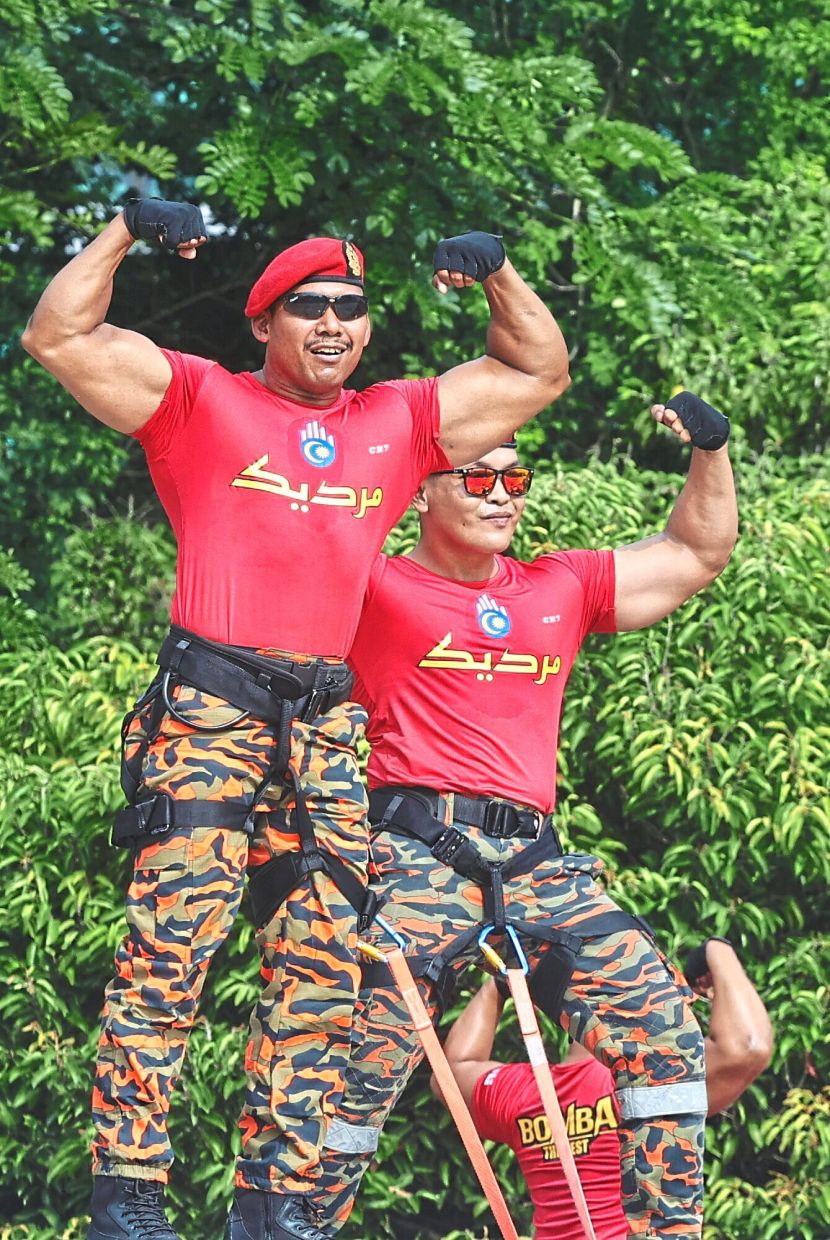 Several ‘Abang Bomba’ from the Fire and Rescue Department flexing their muscles for adoring fans during the parade in Putrajaya.— AZMAN GHANI/The Star