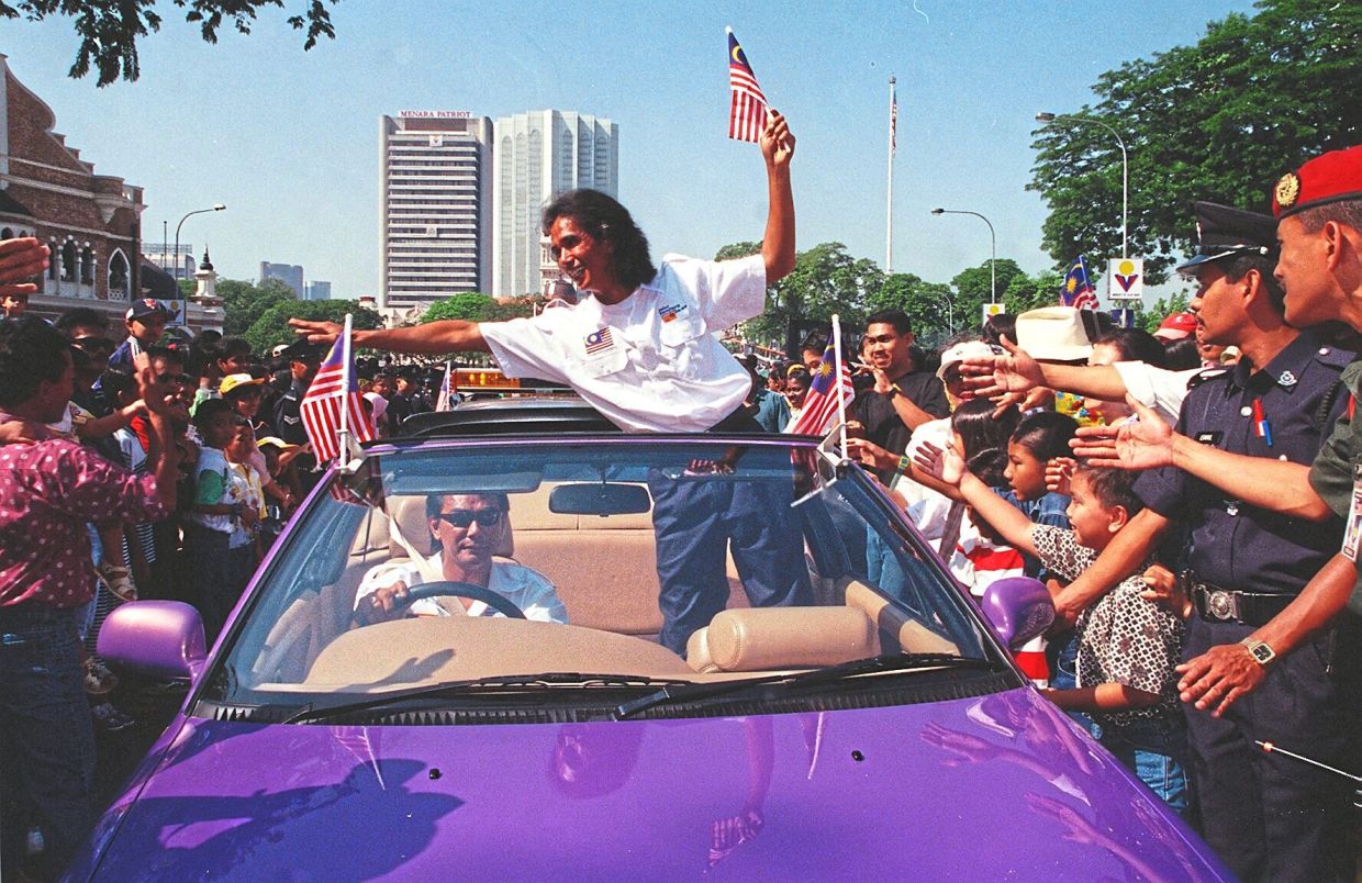Datuk Azhar Mansor, the first Malaysian to sail solo around the world, rode in a purple Proton Cabriolet prototype as he greeted Malaysians during the Merdeka parade. — SIA HONG KIAU/The Star