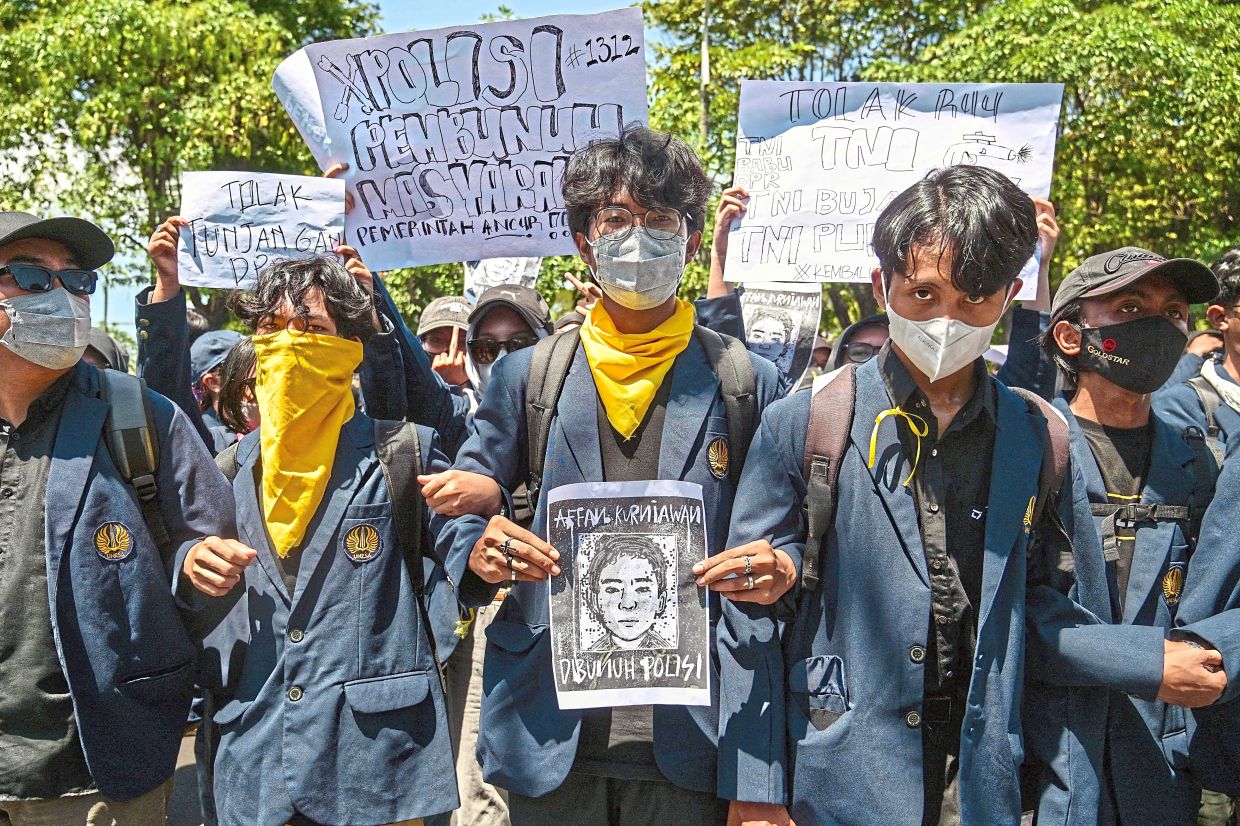 Scenes of unrest: A demonstrator (centre) holding Affan’s portrait during a protest in front of the regional police headquarters in Surabaya.
