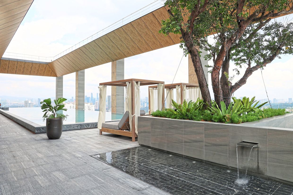 Serviced residences rooftop terrace featuring an infinity pool, cabana seating, lush greenery and expansive city views.