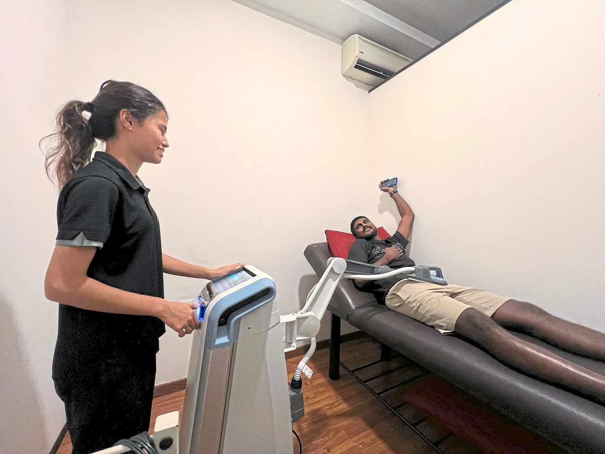 She knows her stuff: Cheryl Lynn Pereira treating a Kuala Lumpur player at the physiotherapy centre. 