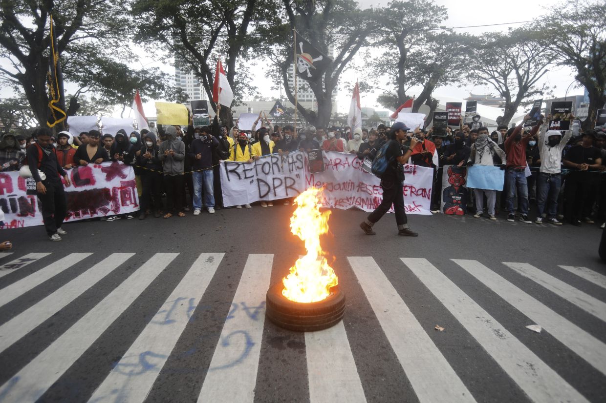 Students burn a tire as they display posters during a protest against lavish allowances given to parliament members, in Medan, North Sumatra, Indonesia, Monday, Sept. 1, 2025. -- AP Photo/Binsar Bakkara
