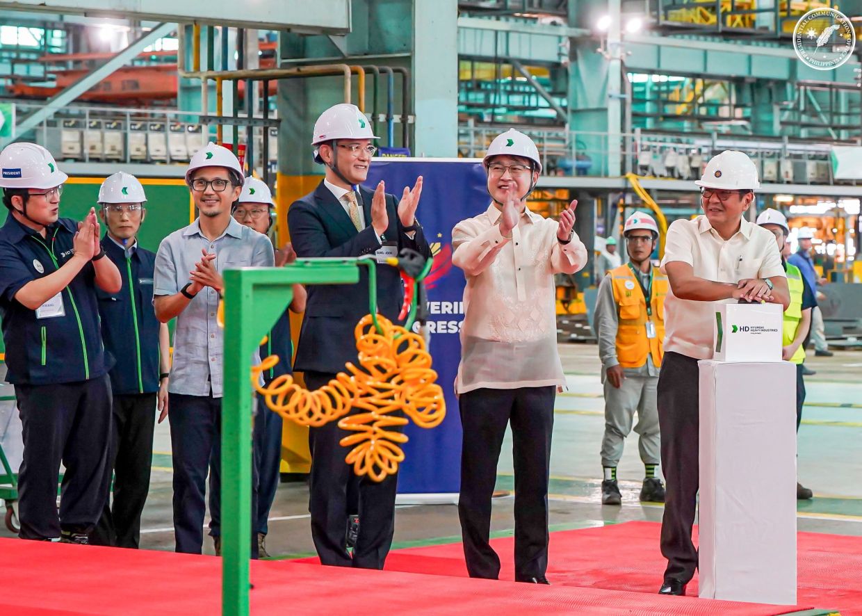 Philippines' President Ferdinand Marcos Jr (right) pressing a button during the inauguration of the Hyundai Shipyard in the province of Zambales. - AFP