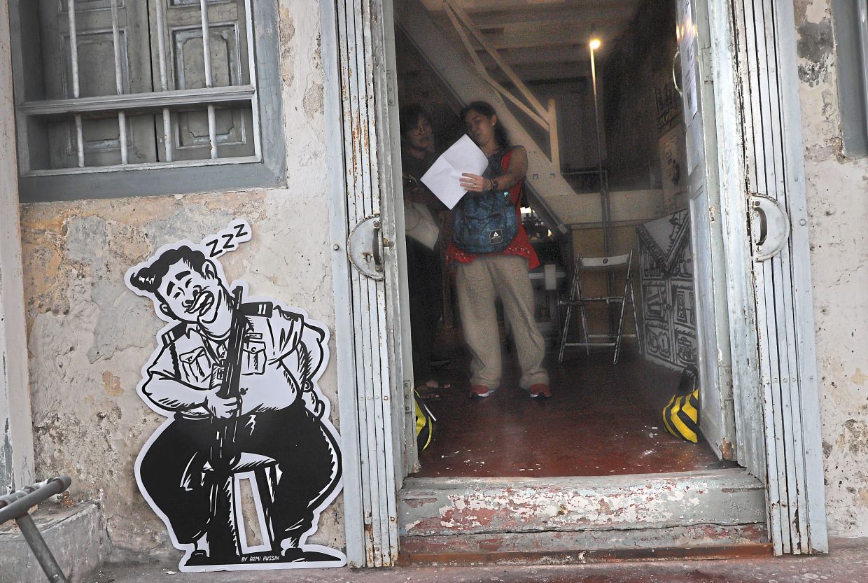 A cutout of a sleeping security guard welcoming visitors to Luma where the main portion of his memorial exhibition was held in George Town.