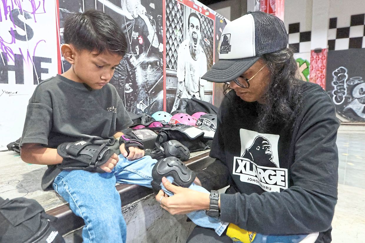 Skateboarding coach Waehamdee Jinawae (right) helping a student to put on safety gear during a skate clinic at Paradigm Mall, Johor Baru.