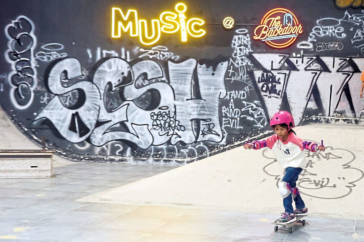 A girl learning to roll and balance on her skateboard during a skate clinic.