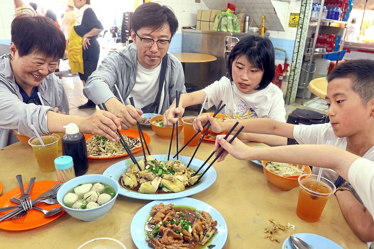Culinary delights, such as Ipoh chicken rice with beansprouts, are a must-try for tourists to the city. Italian tourists Davide (right) and Simone Sbrana (middle) checking out the offerings at a board and card game vendor in Concubine Lane, Ipoh. Visitors say they are impressed with the hospitality of the city’s residents. — Photos: RONNIE CHIN/The Star