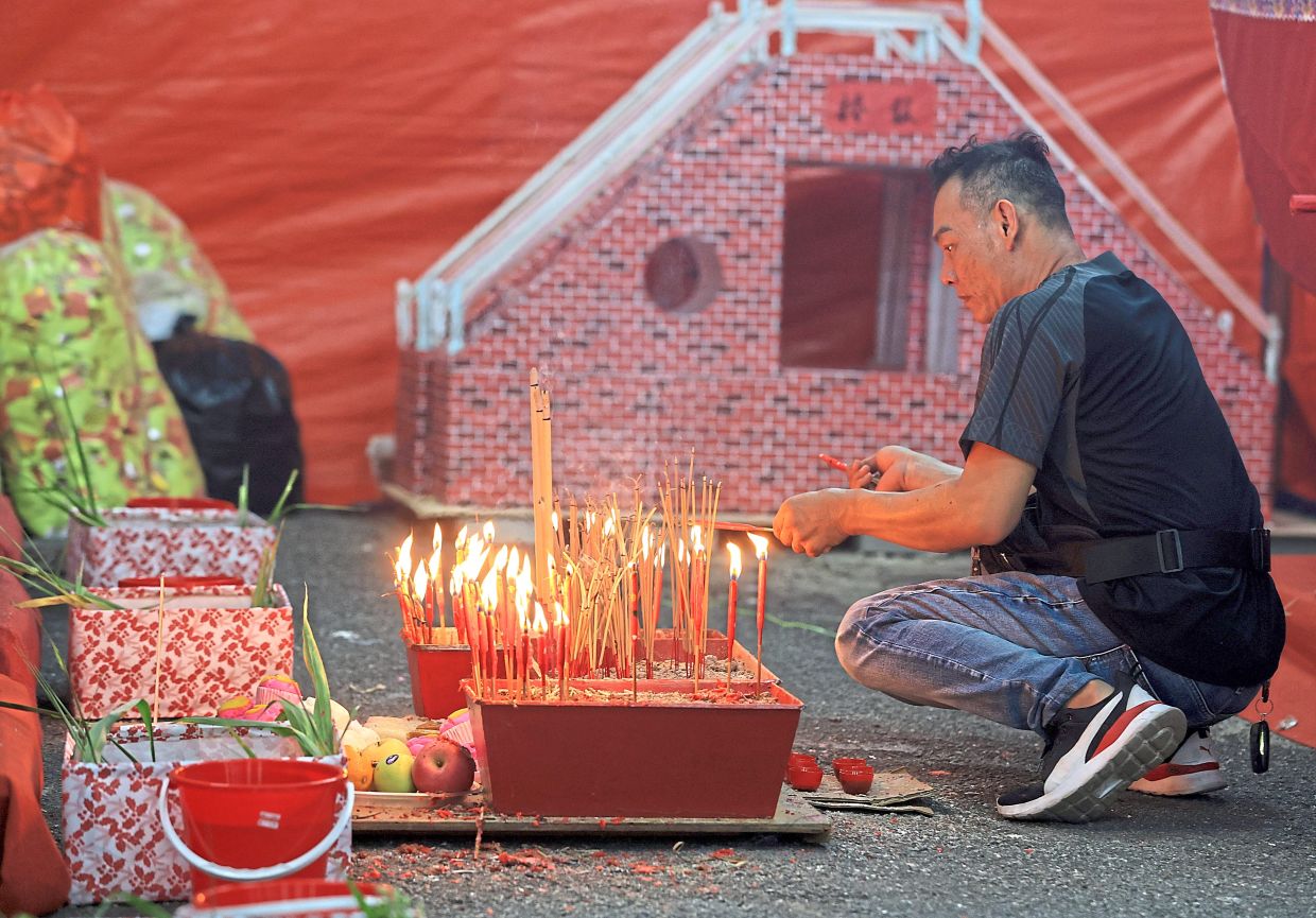 A man burning joss sticks and candles for the departed.