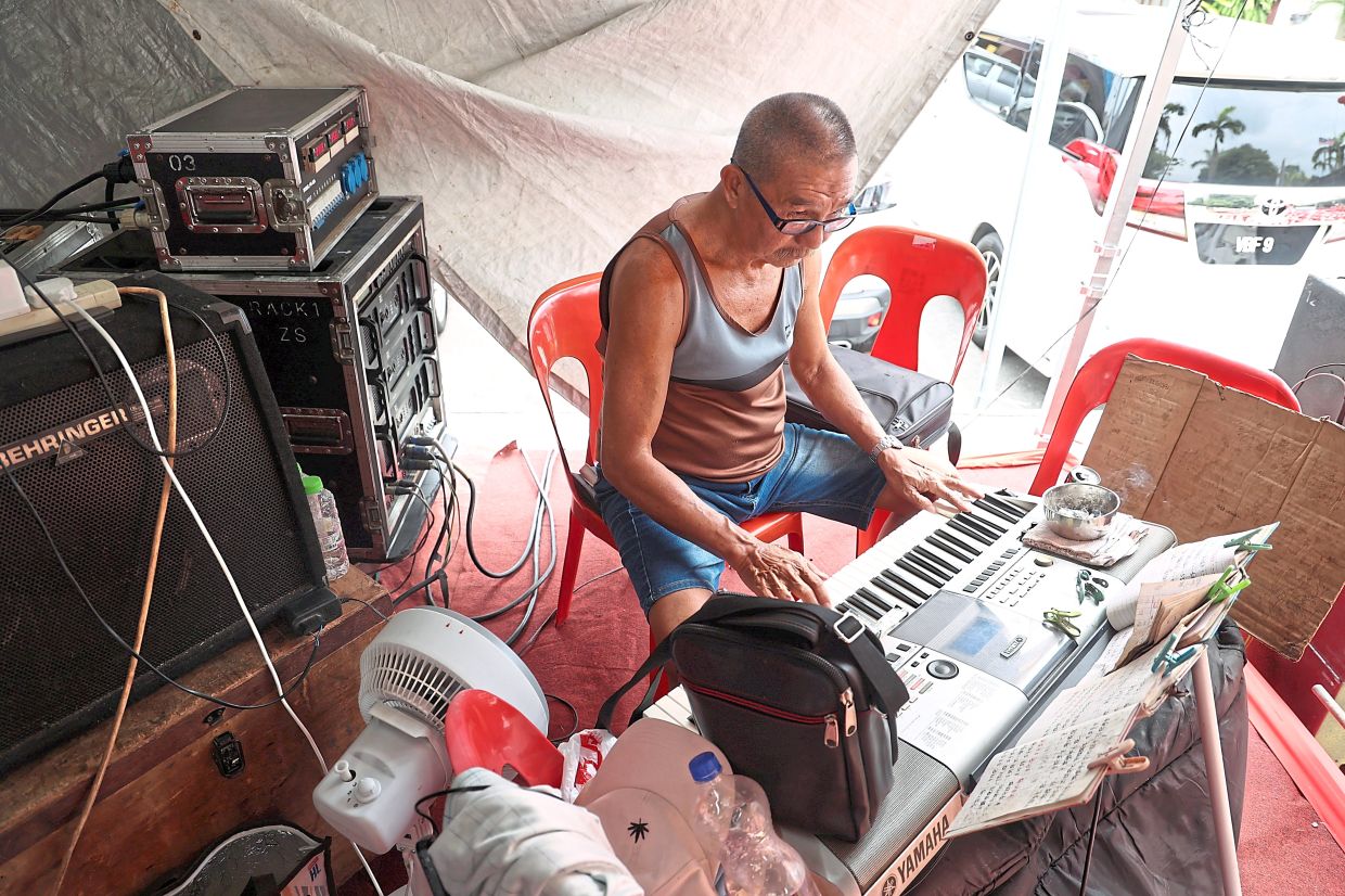 Behind the curtain, a member of the Jin Peng Bu Dai Xi providing the music accompaniment to the glove puppet show.