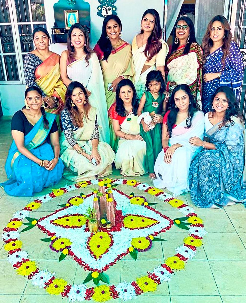 A cultural tradition: Sri Shaila (front row, centre) posing with friends and family next to a pookalam. — Photo courtesy of Sri Shaila