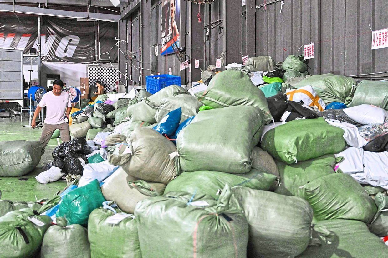 A worker scanning bundles of goods destined for deliveries at a warehouse of the Weijiang International company. — AFP