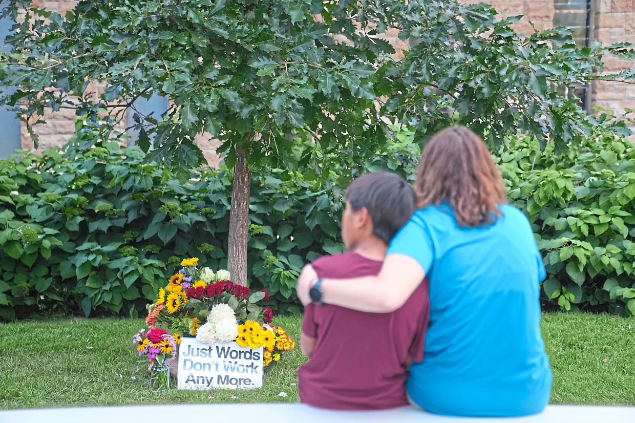 A mother and child sitting across a memorial at Annunciation Catholic Church. — AP