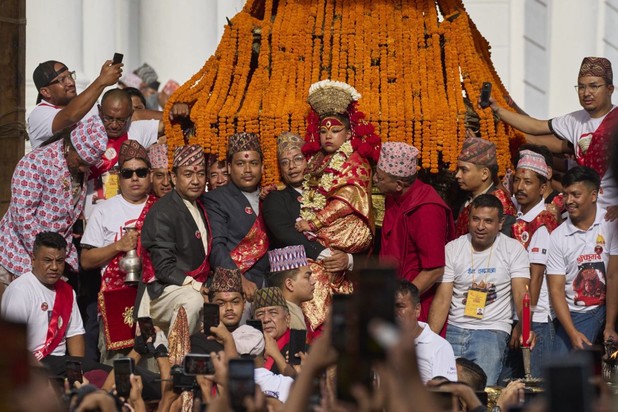 Kumari, Nepal's living goddess, is carried high beside the chariot, which she will ride, pulled by devotees, around the center of the capital in Kathmandu, Nepal. - AP Photo/Niranjan Shrestha