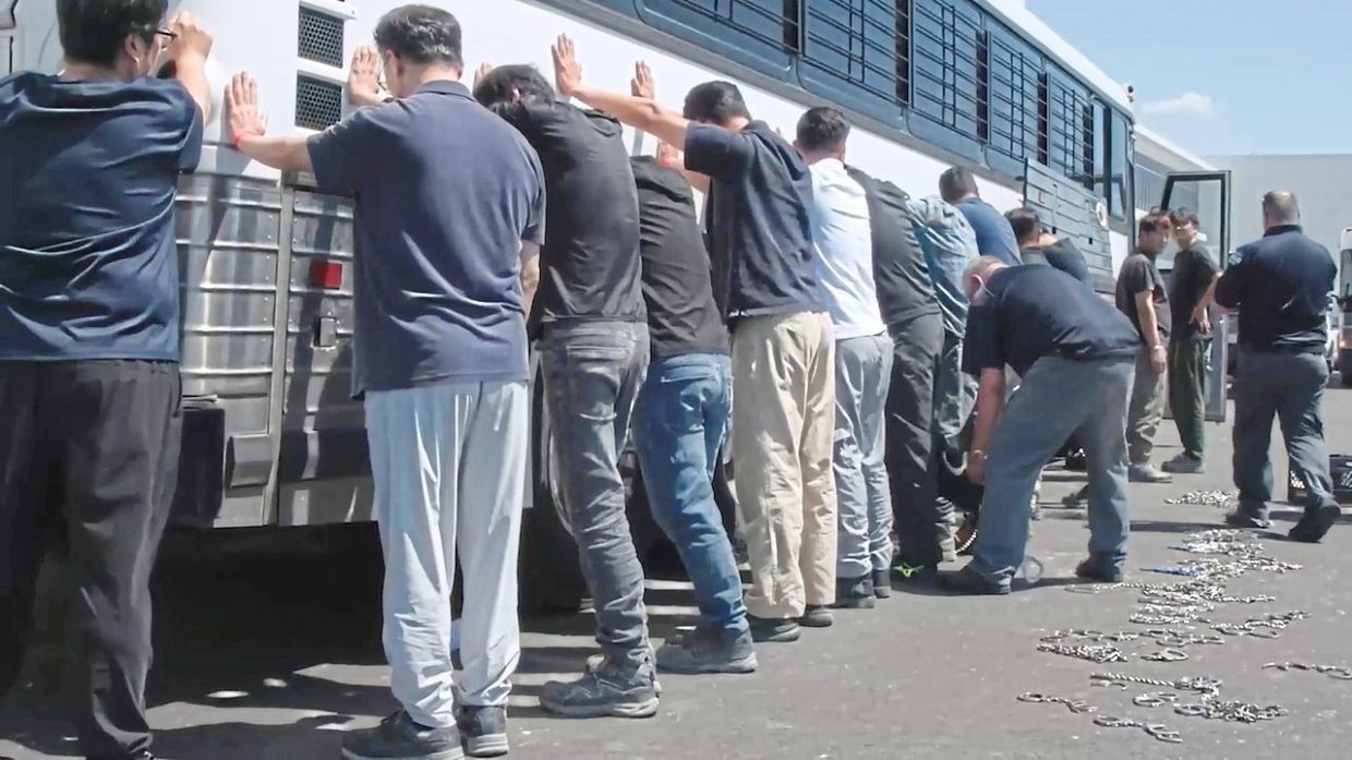 Individuals believedto be South Koreans being chained while standing against a bus. — AFP/ The Korea Herald