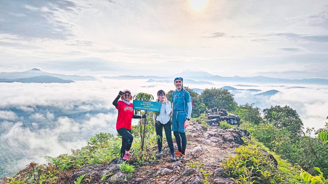 Victory at the summit, with smiles, clouds and the Bukit Botak signboard.
