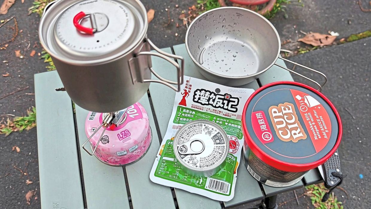 A tiny camping table with food and cooking utensils.