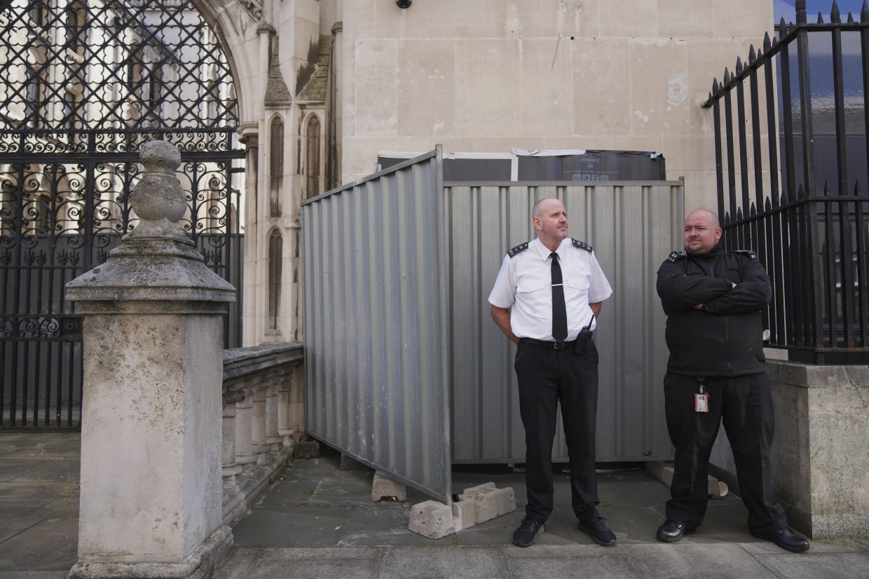 Security officials stand in front of large sheets of black plastic and two metal barriers which conceal Banksy's latest artwork. Photo: AP