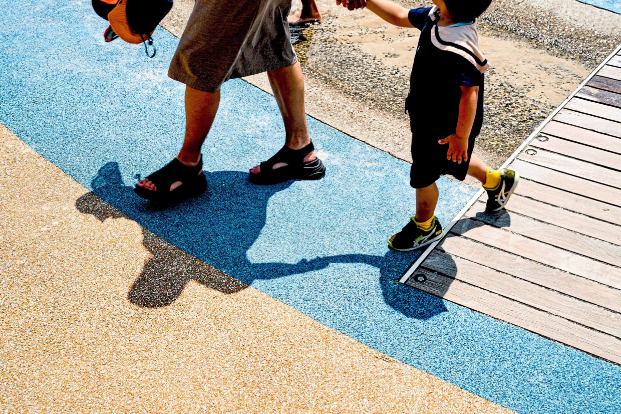 A mother holds her son’s hand at Pier 51 Playground, New York. Photo: SHURAN HUANG/The New York Times