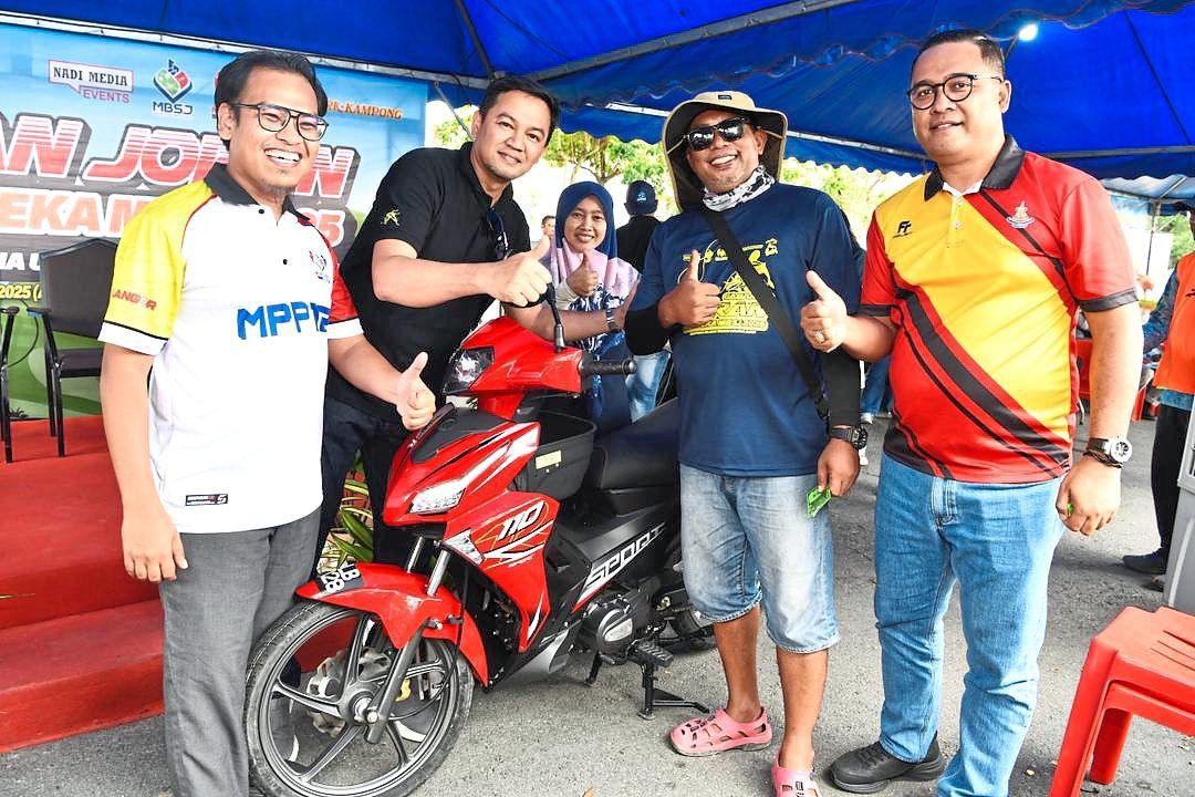 Abbas (right) and Mohd Zulkurnain (second from left) presenting the motorcycle to the lucky draw winner (second from right).