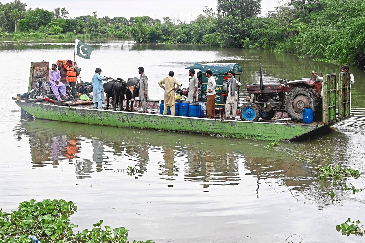 Life-saving efforts: Flood-affected victims with their belongings ­leaving Kasur district. — AFP
