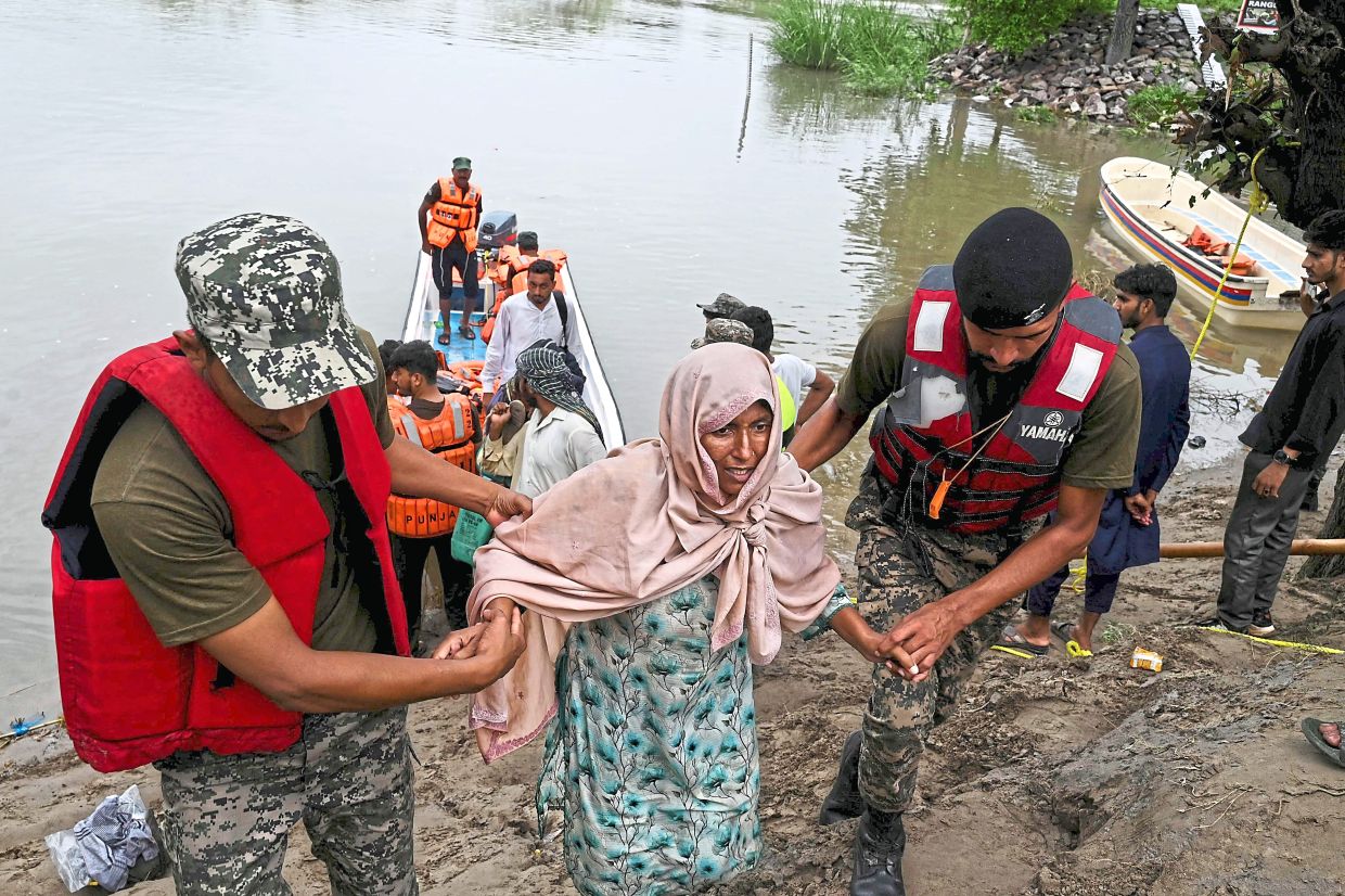 Help at hand: Pakistan Rangers and rescue personnel evacuating flood-affected victims from Kasur district in Punjab province. — AFP