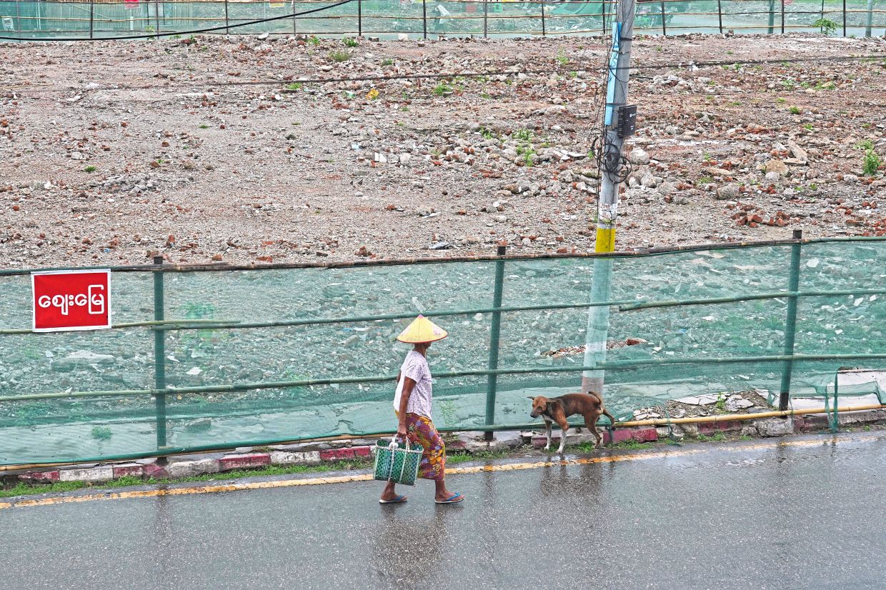 A woman walks past an empty field that once was a local market, destroyed in the March 28 earthquake in Naypyidaw. — AP