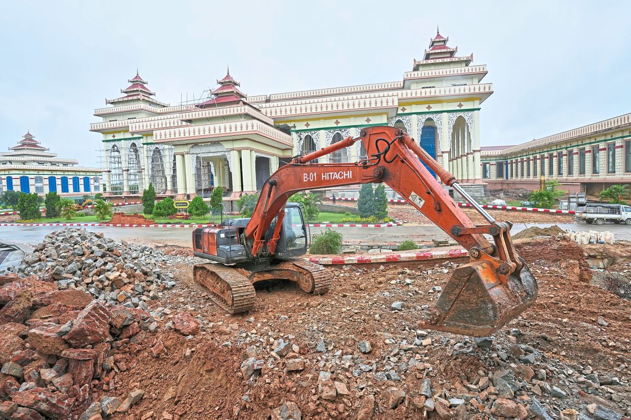 A backhoe clearing an area near the Parliament building that was damaged in the March 28 earthquake in Naypyidaw. — AP