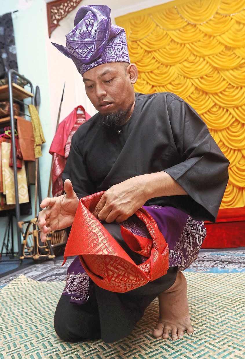 Herin adds the final touches to the tanjak known as ayam patah kepak. 