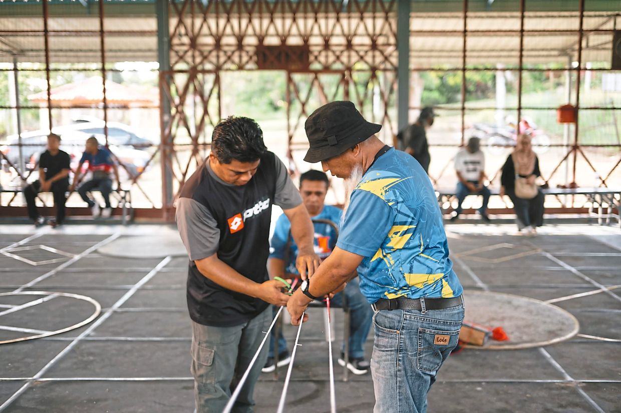 Zulkarin (right) twisting the rope used by gasing pangkah players.