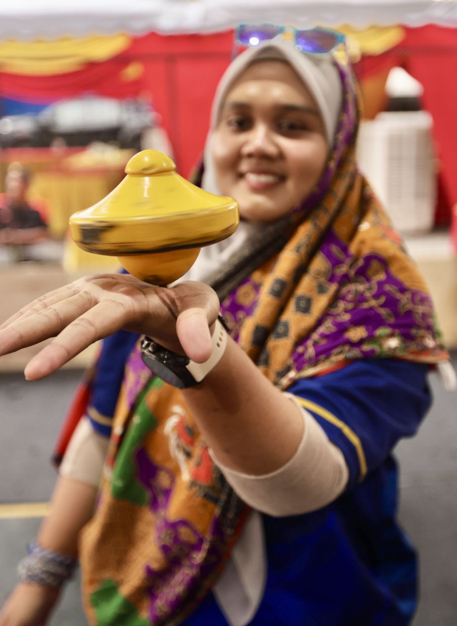 Fatima Massara holding a spinning gasing pangkah in the palm of her hand at PJ Bergasing 2025.
