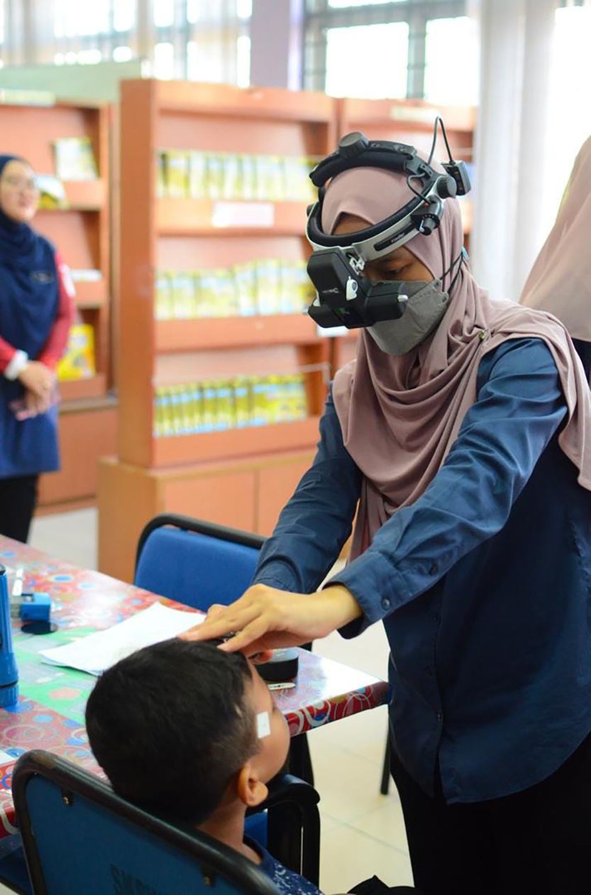 Dr Wardati examines a student’s retina using a portable indirect ophthalmoscope.
