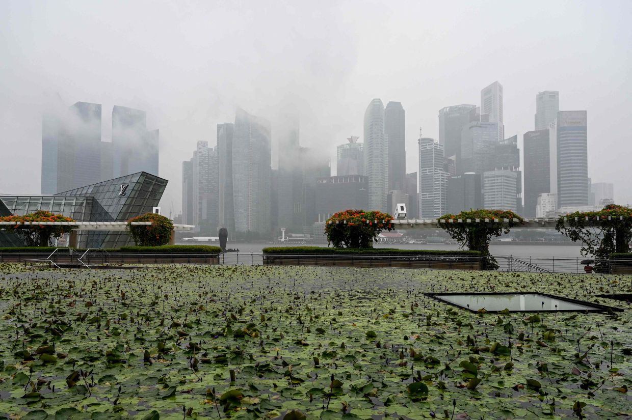 The city skyline is shrouded in rain clouds in Singapore. -- Photo by Roslan RAHMAN / AFP