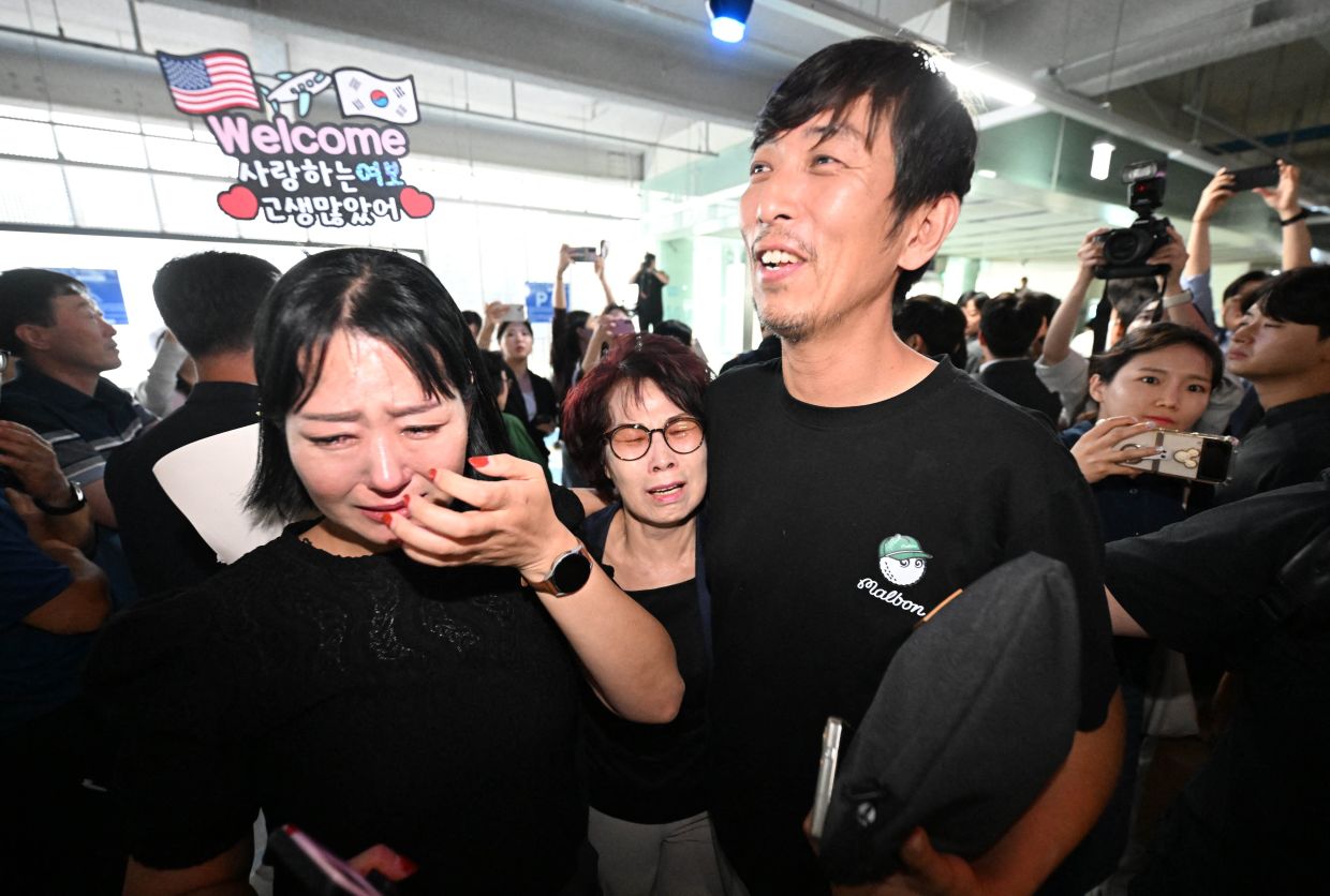 A South Korean worker (right), who was detained in a US immigration raid at a Hyundai-LG plant in Ellabell, Georgia, is welcomed by family members after returning from Atlanta at a parking lot in Incheon International Airport in Incheon on September 12, 2025. A specially chartered flight carrying hundreds of South Korean workers detained in a US immigration raid last week landed at Incheon International Airport on Friday, September 12, AFP reporters saw. - Photo by YONHAP / AFP