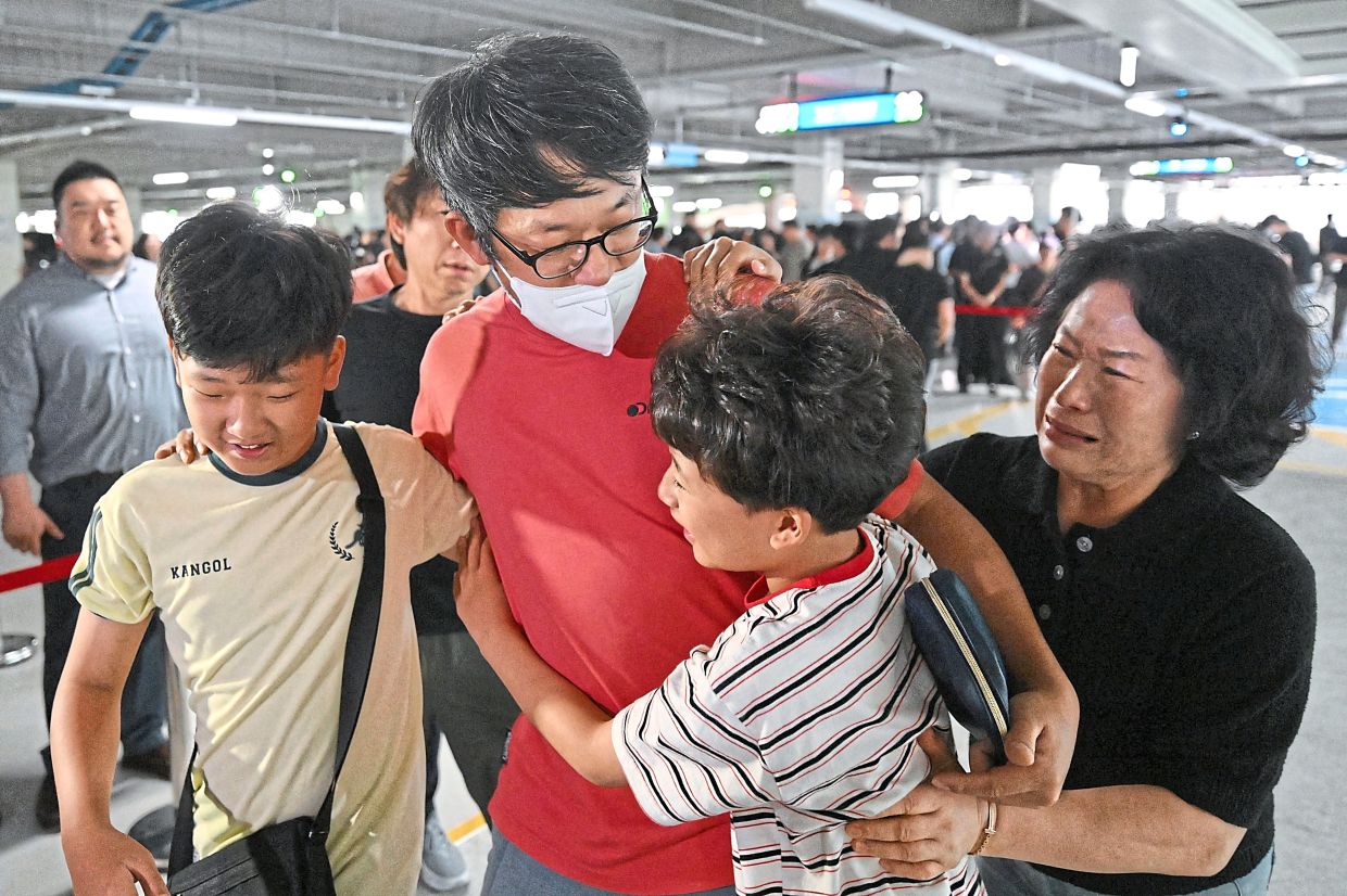 Family members embracing South Korean workers upon their return from Atlanta. — AFP/Reuters
