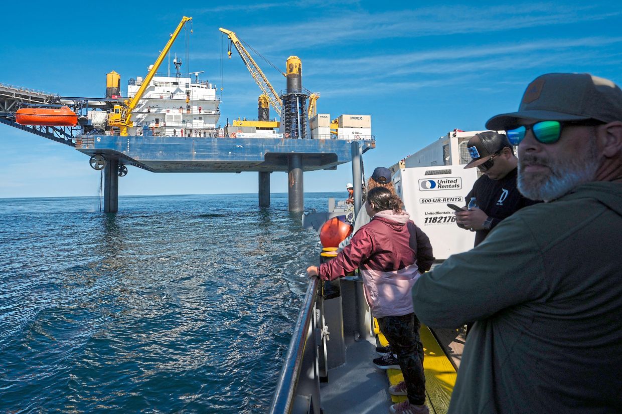 Expedition 501memberslooking downfrom the‘Liftboatrobertplatform’, totheapproachingGaspee, acrew transportvessel, in theNorth atlantic.— AP