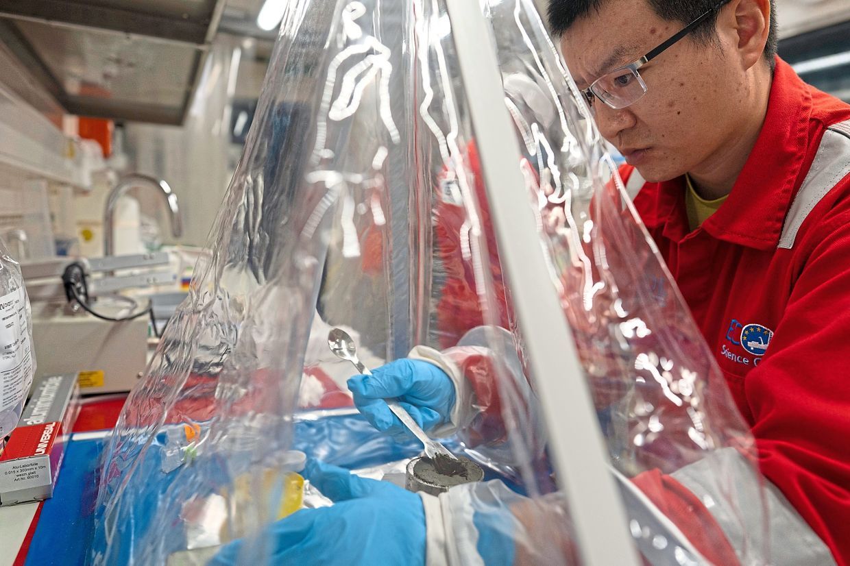 Researcher Xinxu Zhang of Shenzhen university China, working in a container to ensure a sterile environment. — AP