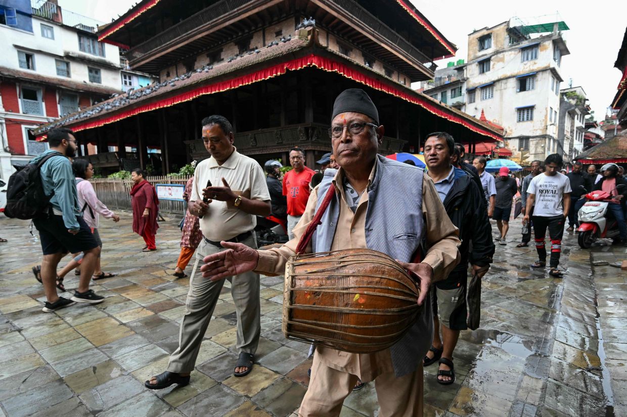 Hindu devotees chant devotional songs as they walk at the Durbar Square in Kathmandu on Saturday, September 13, 2025. Nepal's capital, on Saturday, took a step back towards normality after deadly anti-corruption protests, as daily life returned with a curfew eased and an interim prime minister sworn into office. -- Photo by Arun SANKAR / AFP