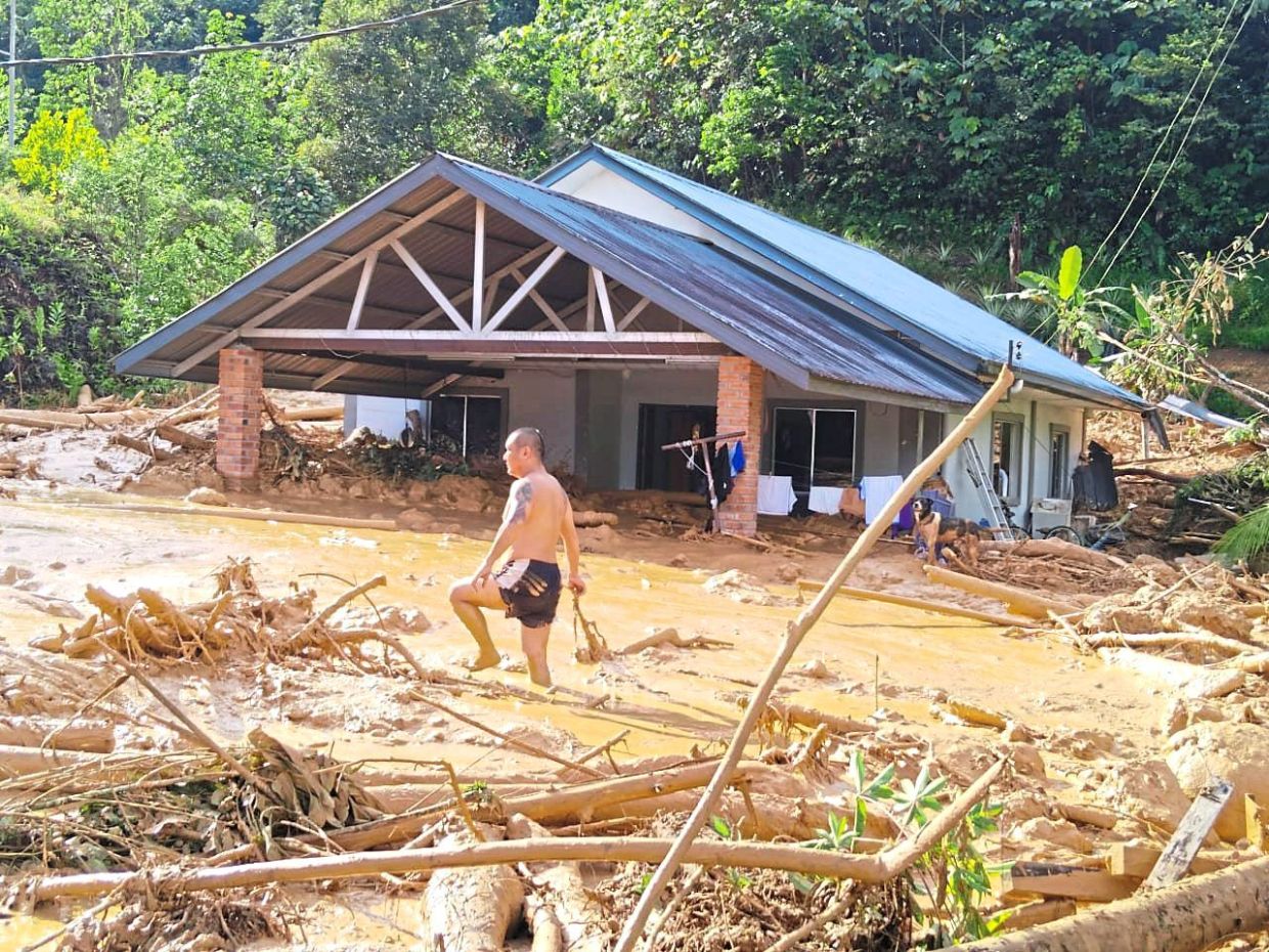 All swamped: Oliver wading through mud to check on his damaged house.