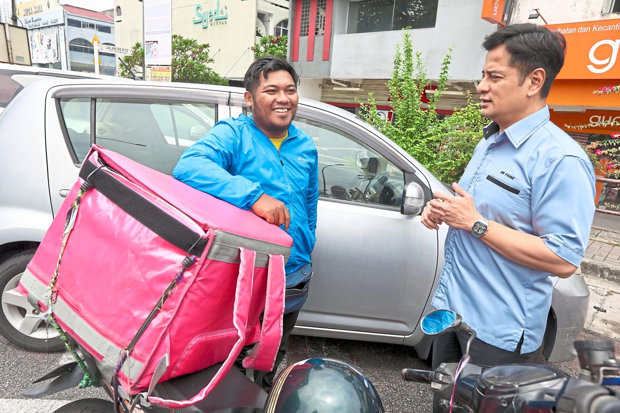 Mohammad Fahmi (right) speaking to food delivery rider Syahir Shaffie, 27, to get his feedback on a proposed hub to be built in SS2, Petaling Jaya.