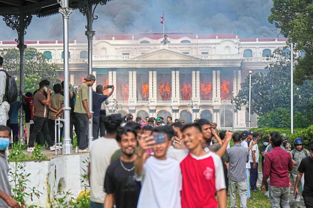 Sending a message: Protesters celebrating at the Singha Durbar, the seat of the Nepal government’s various ministries and offices, after it was set on fire during a protest against a social media ban and corruption in Kathmandu, Nepal. — AP