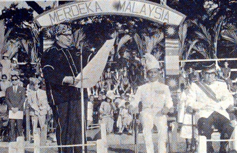 Sabah Chief Minister Tun Fuad Stephens reading the proclamation of Independence of Sabah through the formation of Malaysia in 1963. With him are Yang di-Pertua Negeri Sabah Tun Mustapha Datu Harun. Also present is deputy prime minister of Malaya, representing the Federal Government of Malaysia, Tun Abdul Razak. — Arkib Negara Malaysia